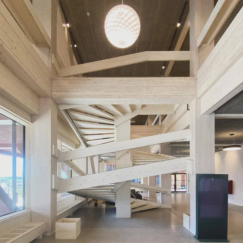 Interior view of the cross-laminated timber staircase structure with exposed beams and a spherical pendant light