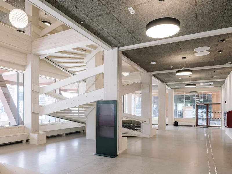 Interior lobby with pale timber staircase and exposed concrete ceiling under pendant lights
