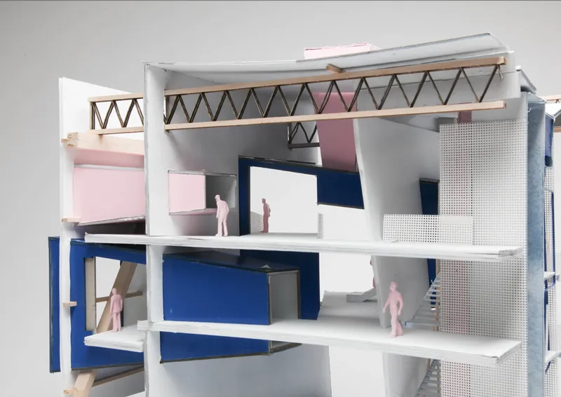 Section model showing zigzag roof truss above split-level interior spaces with pink figures and perforated metal screens