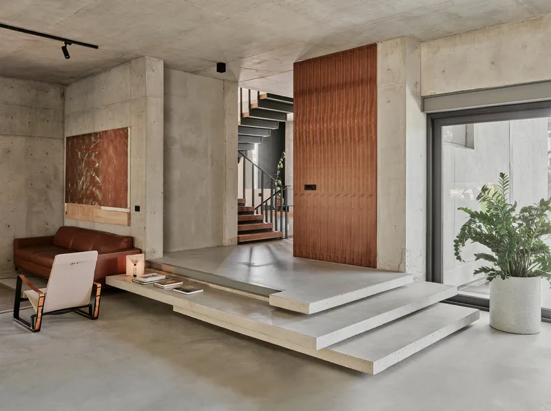 Raised platform with timber staircase and wood-paneled wall flanked by concrete columns
