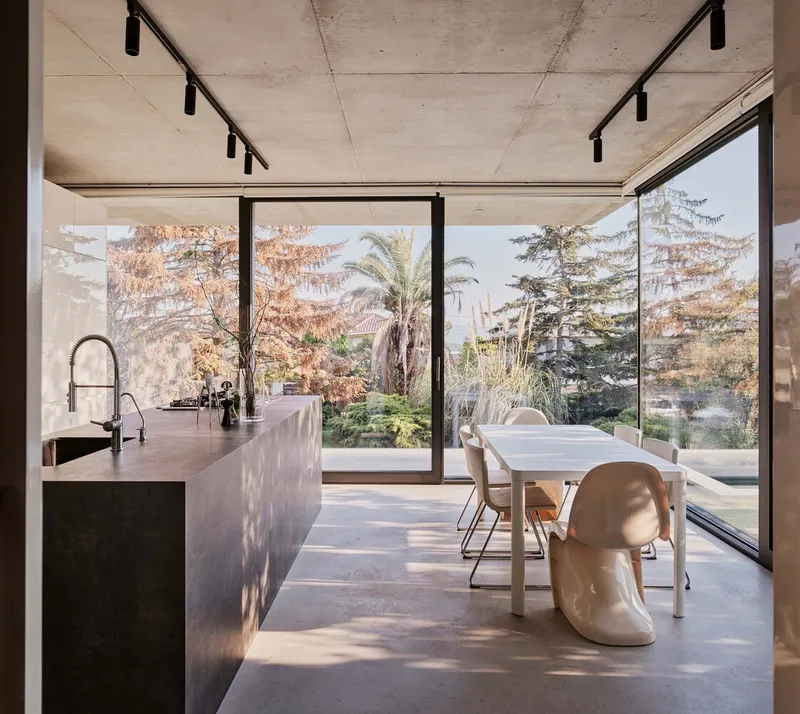 Dining area with polished concrete island and glazed doors opening to the garden