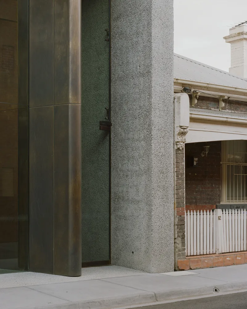 Close-up of terrazzo column edge meeting bronze panel and adjacent heritage structure