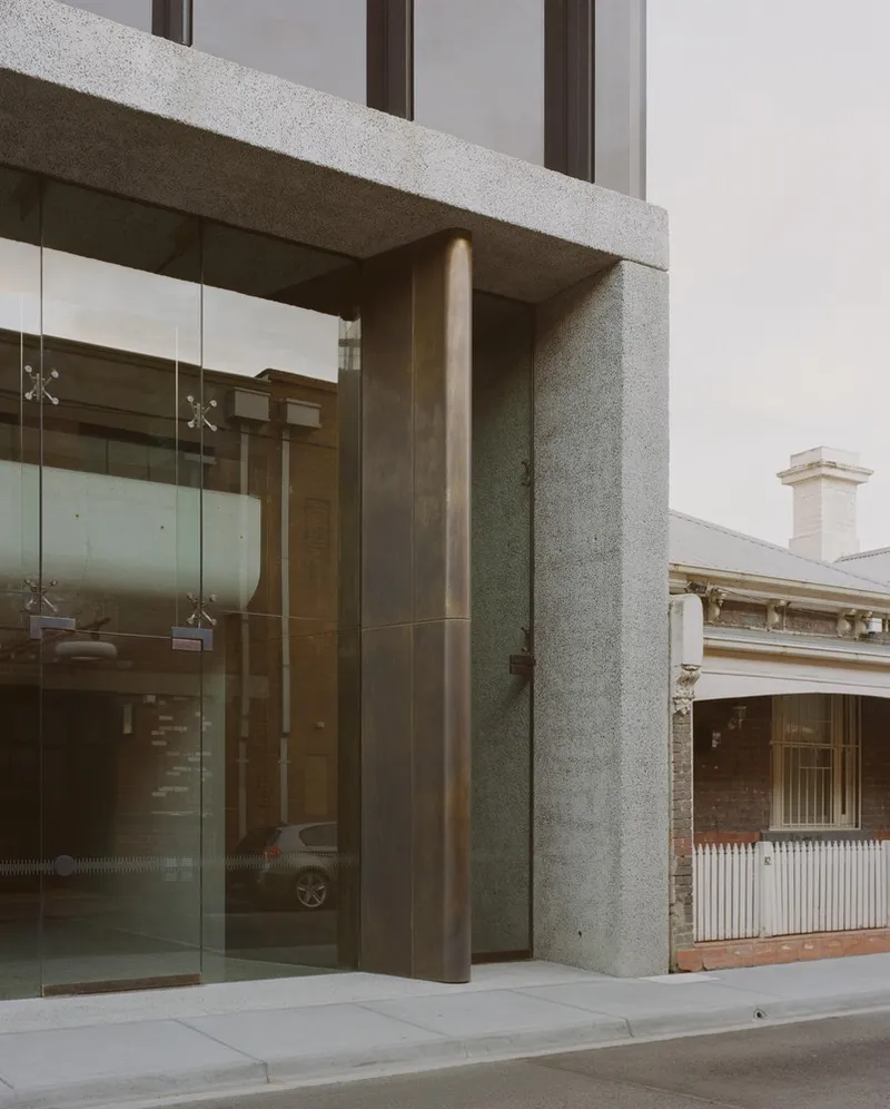 Entry portal detail with terrazzo column and bronze cladding alongside glass doors
