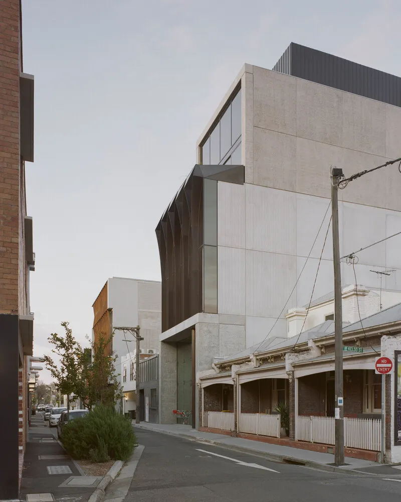 Street view showing angular facade volumes with terrazzo and bronze cladding beside heritage buildings