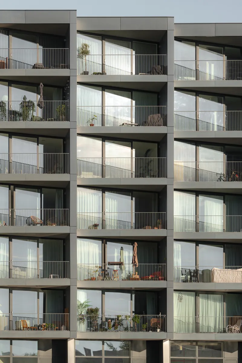 Stacked concrete balconies with metal railings and sliding glass doors under overcast sky