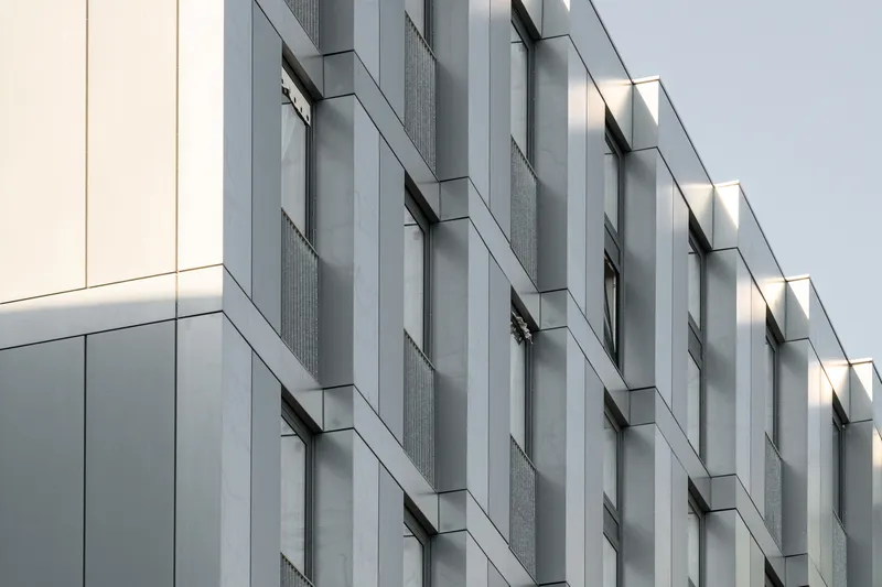 Facade detail showing staggered metal panels with recessed vertical window openings and textured cladding