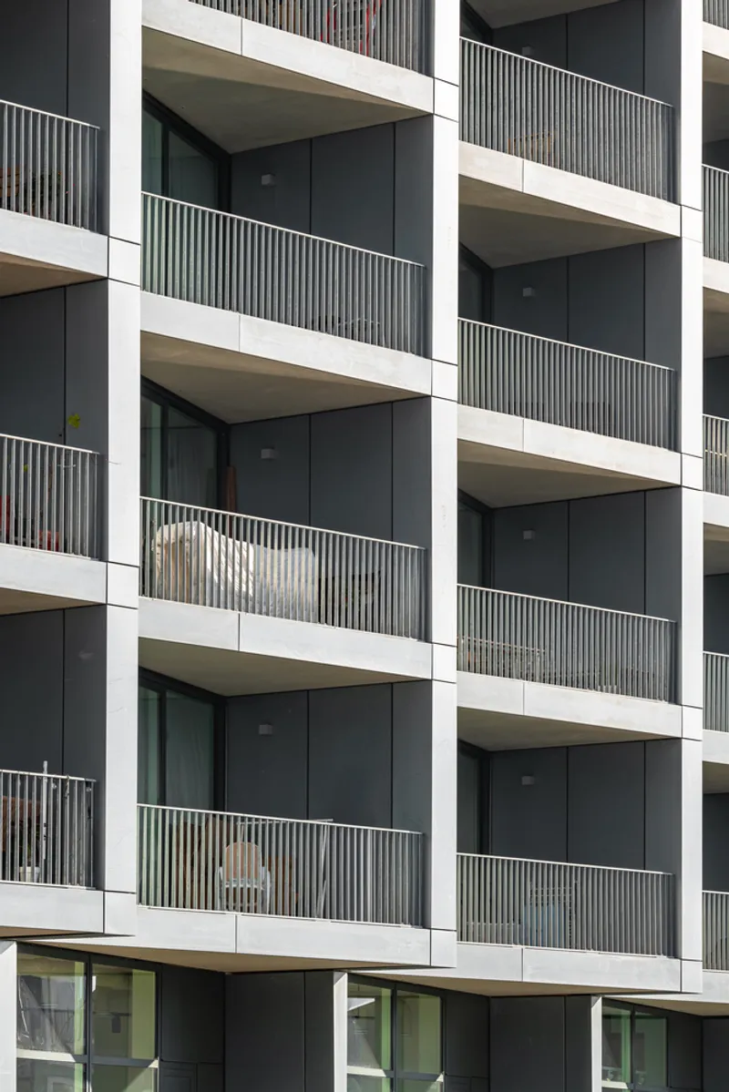 Stacked balconies with vertical timber slat screens and white concrete slab edges in daylight
