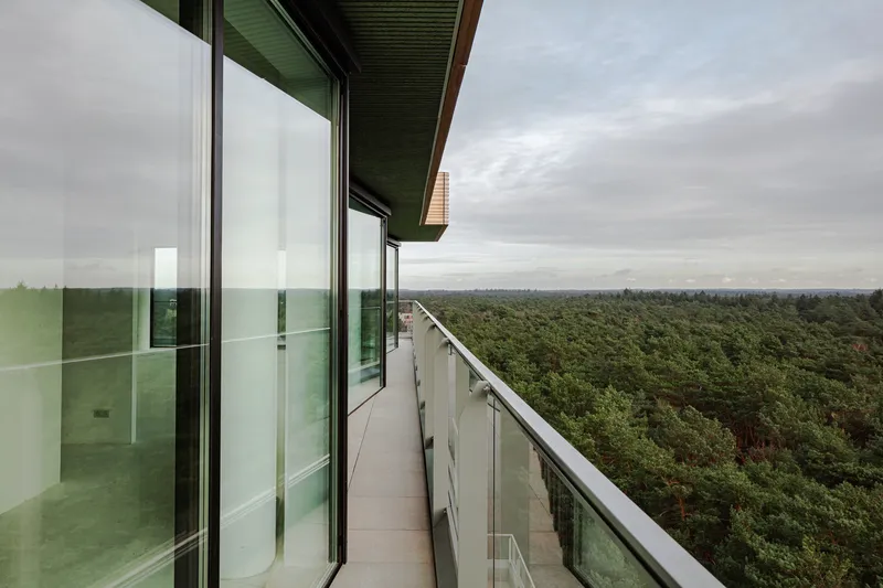 Covered balcony overlooking dense forest canopy under an overcast sky
