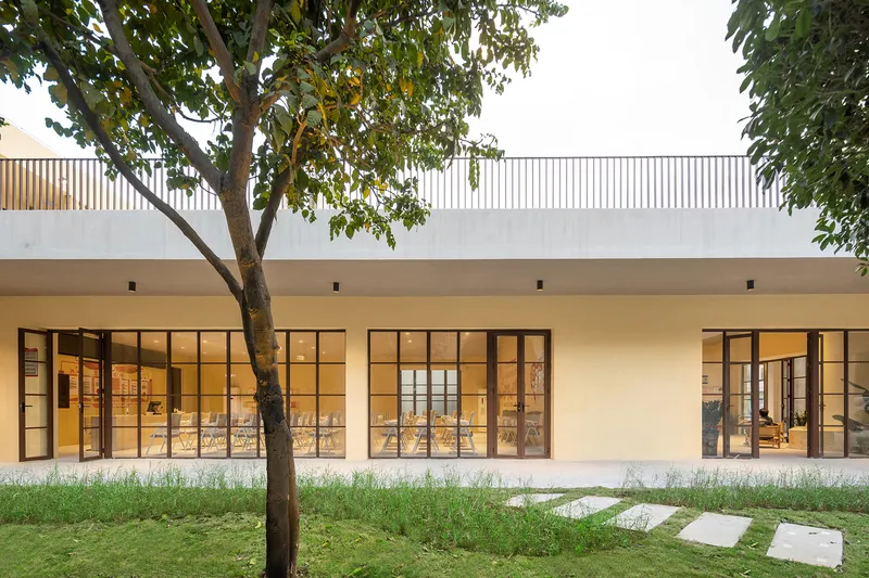 Steel-framed glass doors opening onto a courtyard with a deciduous tree and grass