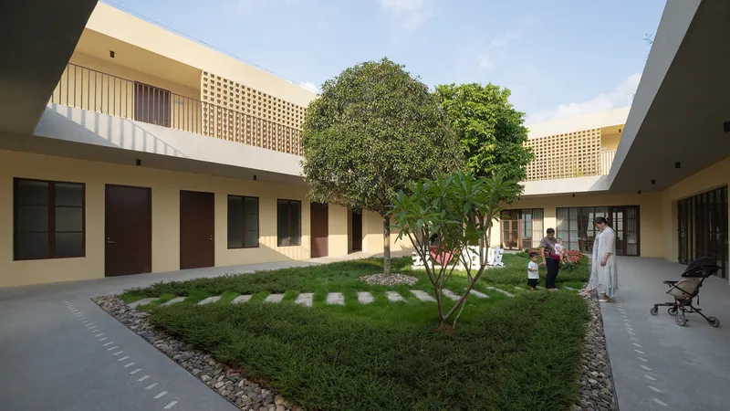Interior courtyard with grass, stepping stones and central tree surrounded by two-storey classroom wings