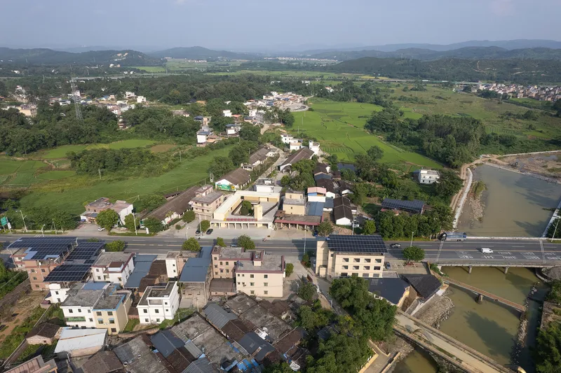Aerial view of the village cluster with terraced volumes along a river and surrounding agricultural fields