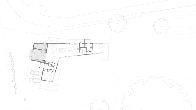 Floor plan drawing depicting the angled residence with parking area and adjacent tree placements