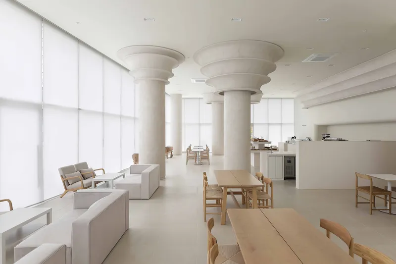Interior dining hall with fluted cylindrical columns and translucent fabric screens filtering daylight