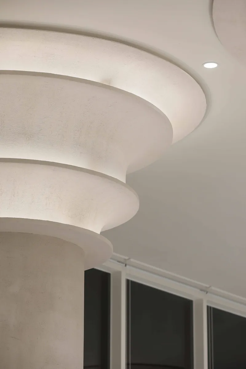 Close-up of a layered ceiling capital with concentric stepped rings meeting a flat white soffit