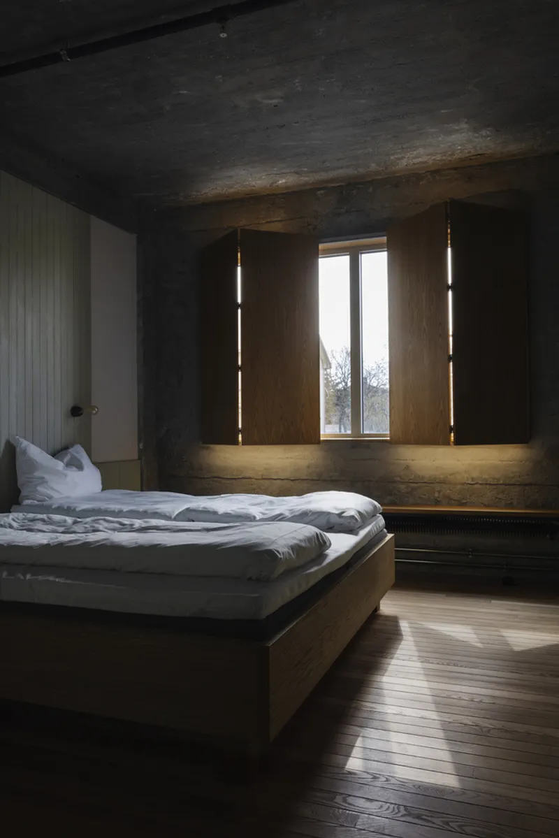 Bedroom with timber platform bed and flanking vertical light strips in dark wood millwork