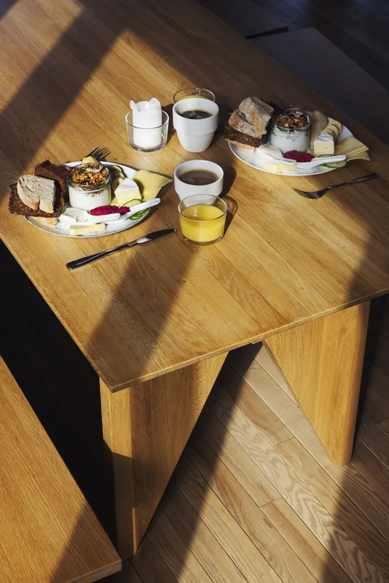 Oak table with breakfast plates and cups set in angled morning light