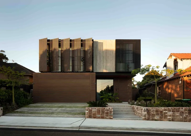 Street view of the vertical timber screen facade with recessed concrete panel and brick planter steps