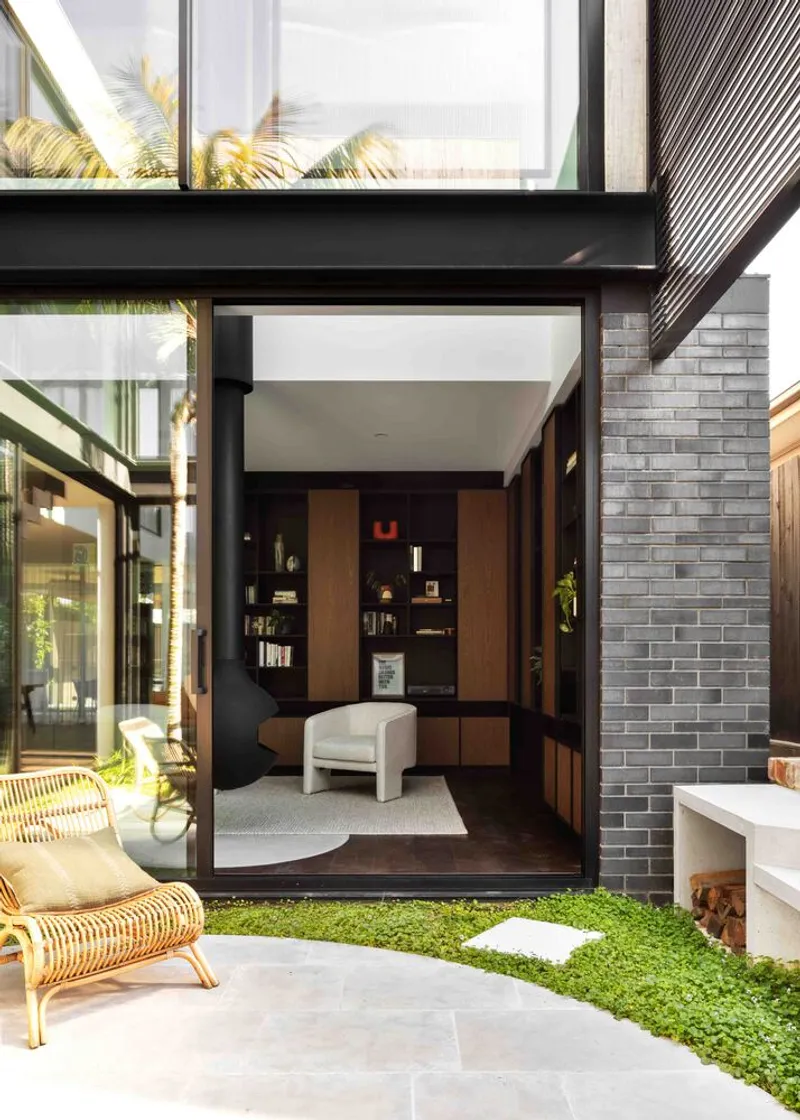 Courtyard with floor-to-ceiling glass doors framing the study and green lawn in afternoon light