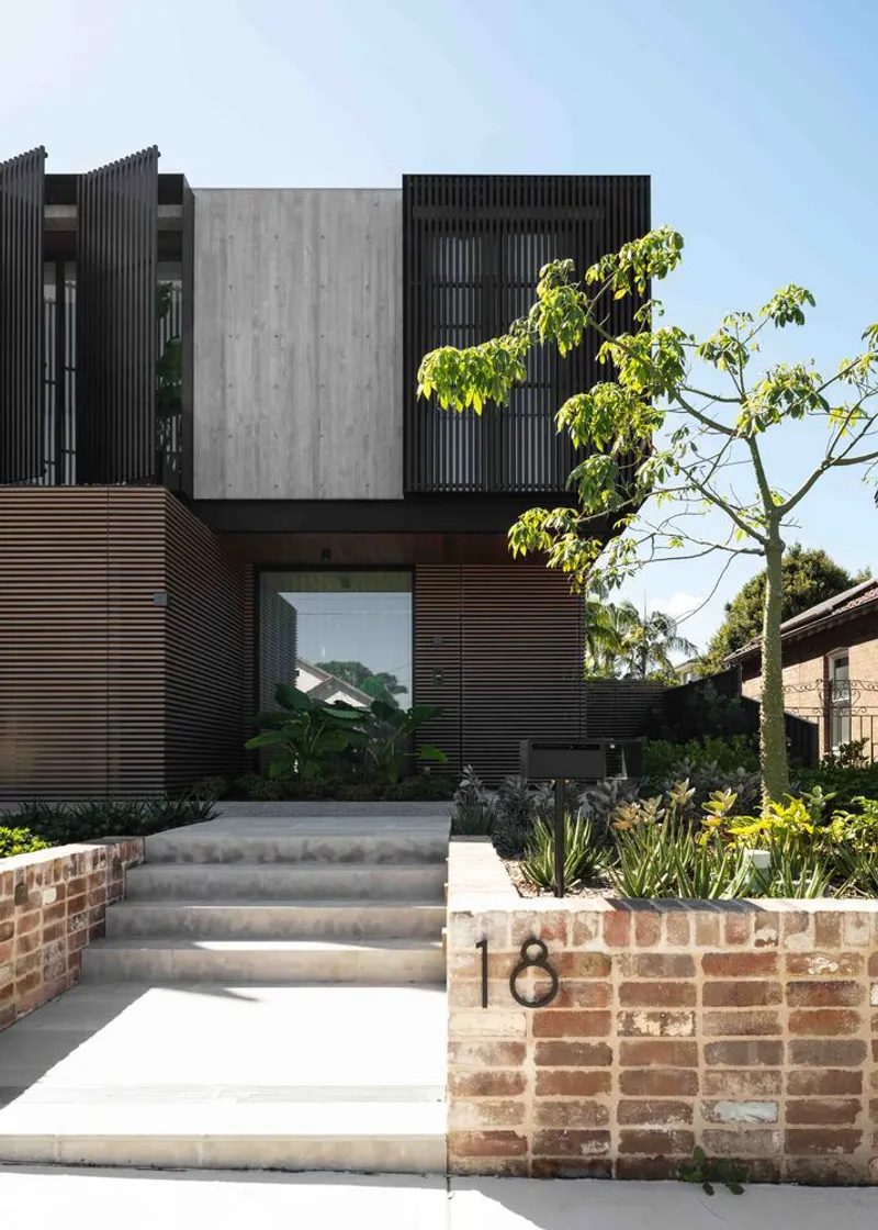 Front entry steps in brick and concrete with timber slat facade and mature tree in foreground