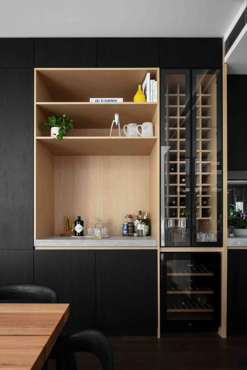 Built-in shelving niche in timber with wine rack and storage below black upper cabinetry
