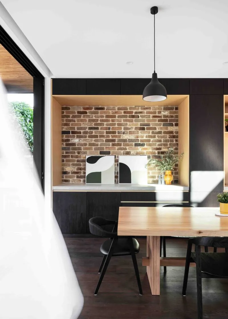 Dining area with exposed brick wall in timber-lined alcove and pendant light above