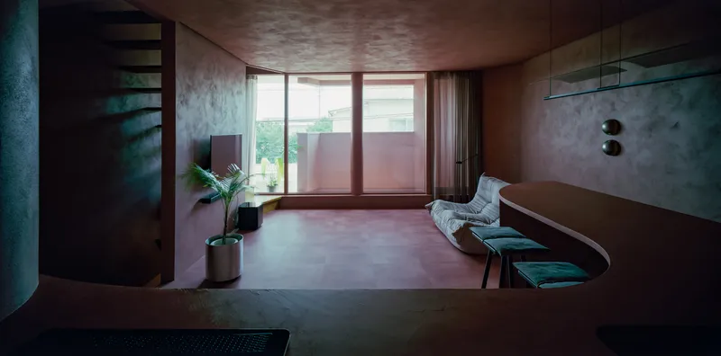 Living space with full-height windows, curved built-in seating and spiral staircase in afternoon light