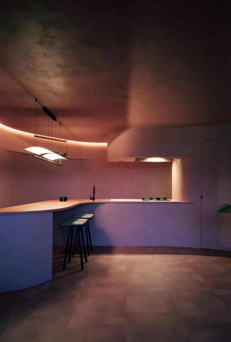 Kitchen at dusk with warm linear lighting under upper cabinetry and ceiling cove illumination