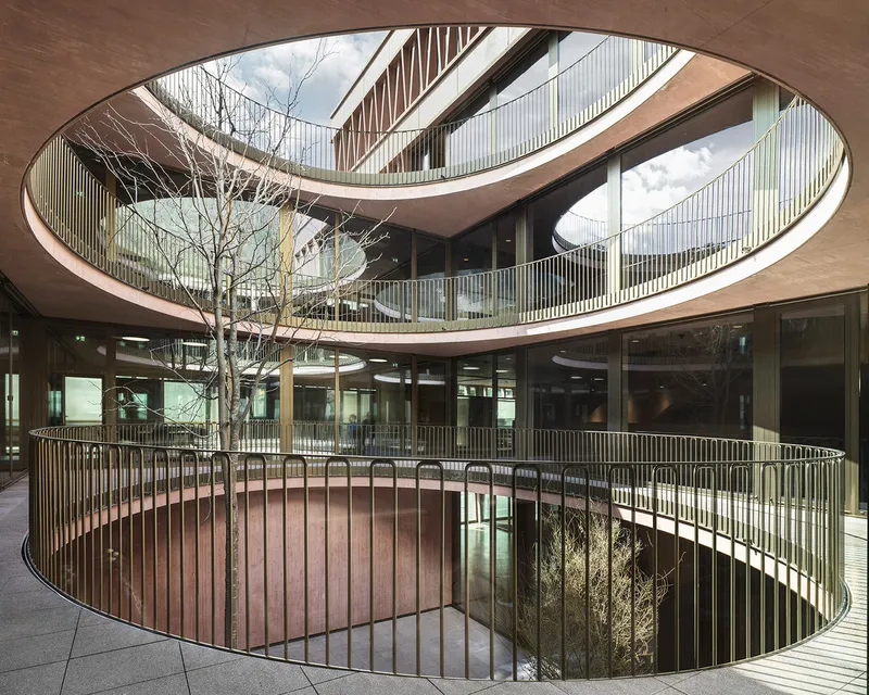Aerial view of the circular courtyard with metal railings, planted trees, and curved balconies