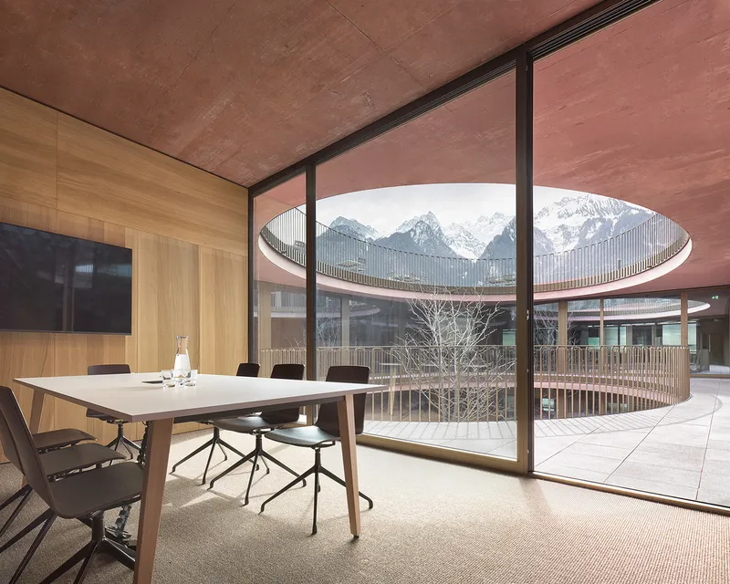 Conference room with floor-to-ceiling glazing overlooking the courtyard and snow-capped mountain peaks