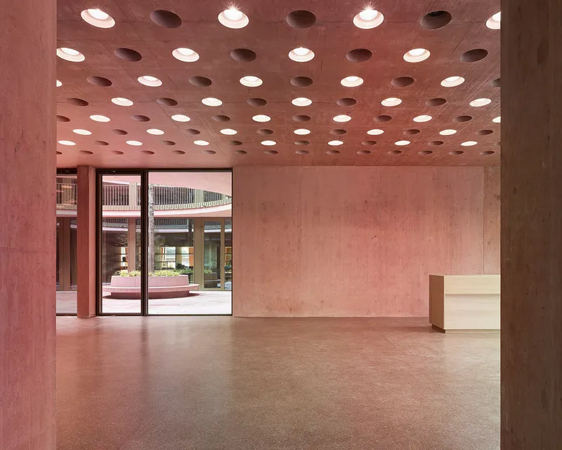 Entry foyer with perforated pink ceiling, terrazzo floor, and glazed doors opening to an interior courtyard