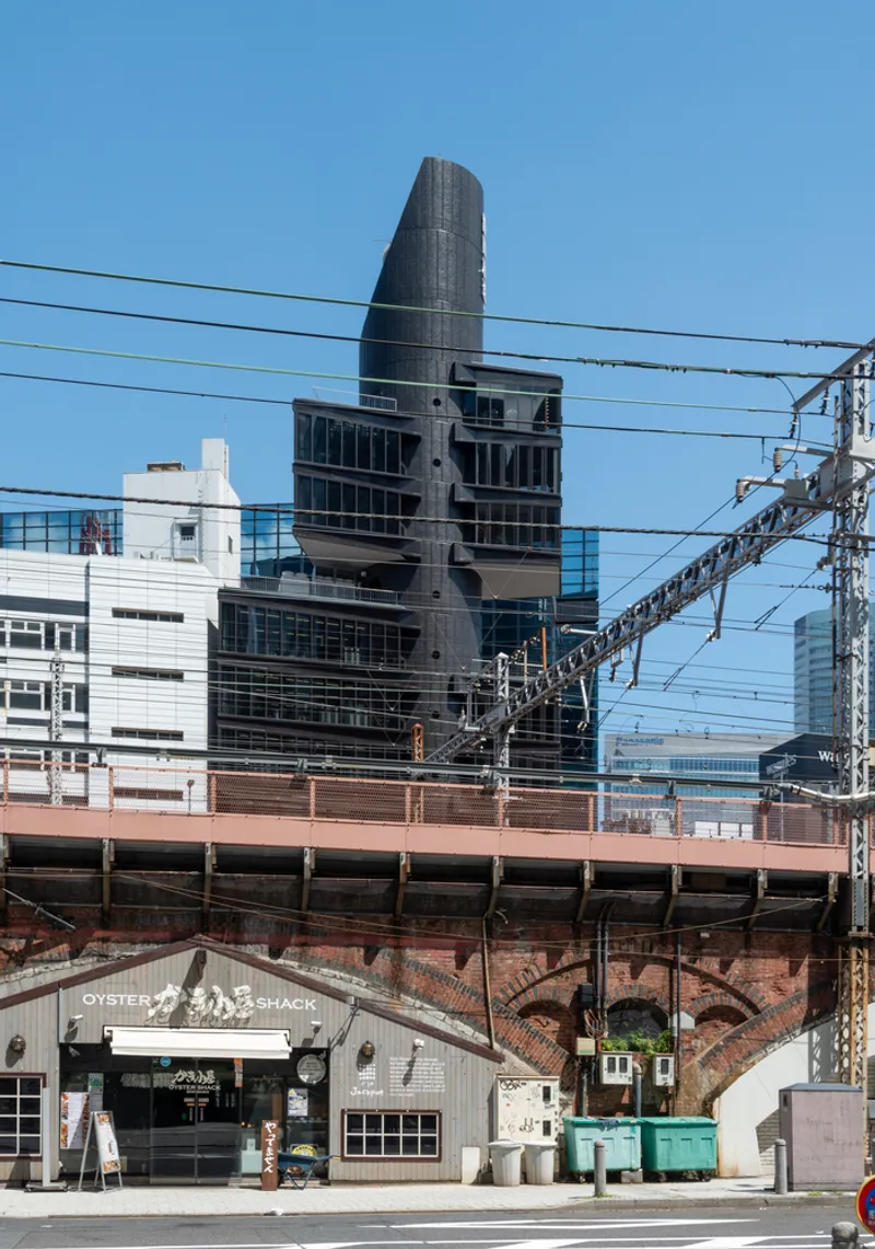 Stacked tower with cantilevered floors seen beyond overhead railway tracks and brick viaduct arches