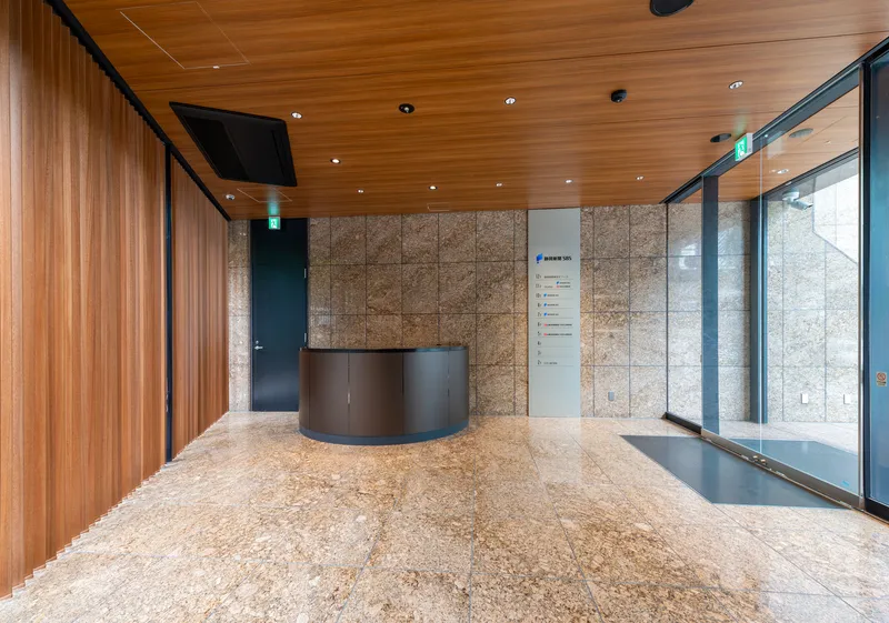Lobby with curved reception desk, timber ceiling, and textured stone wall