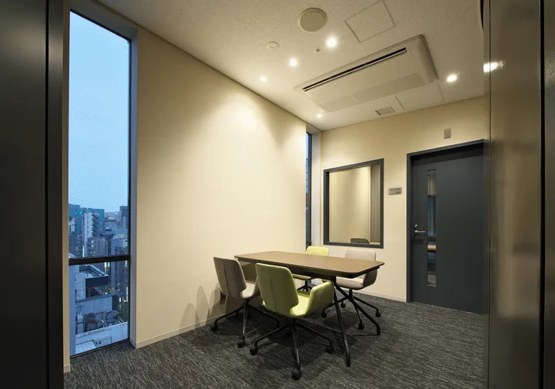 Meeting room with tall windows overlooking the city at dusk and carpet flooring