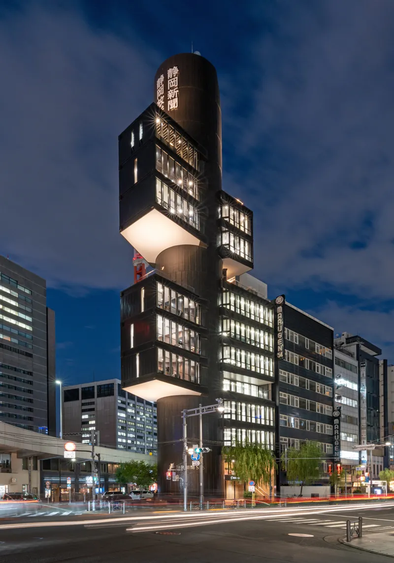 Night view of the tower with glowing interiors and vertical signage on the curved volume