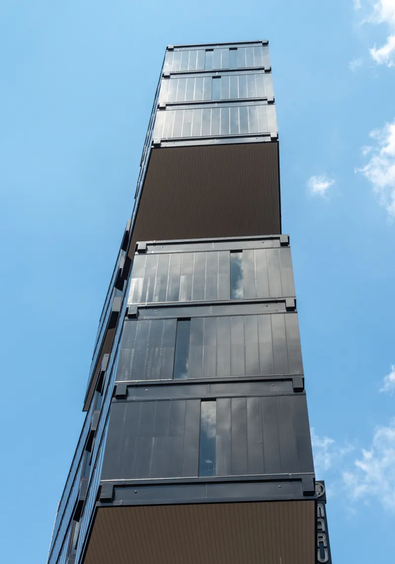 Tapered tower elevation showing alternating glass and ribbed metal panel floors against a blue sky