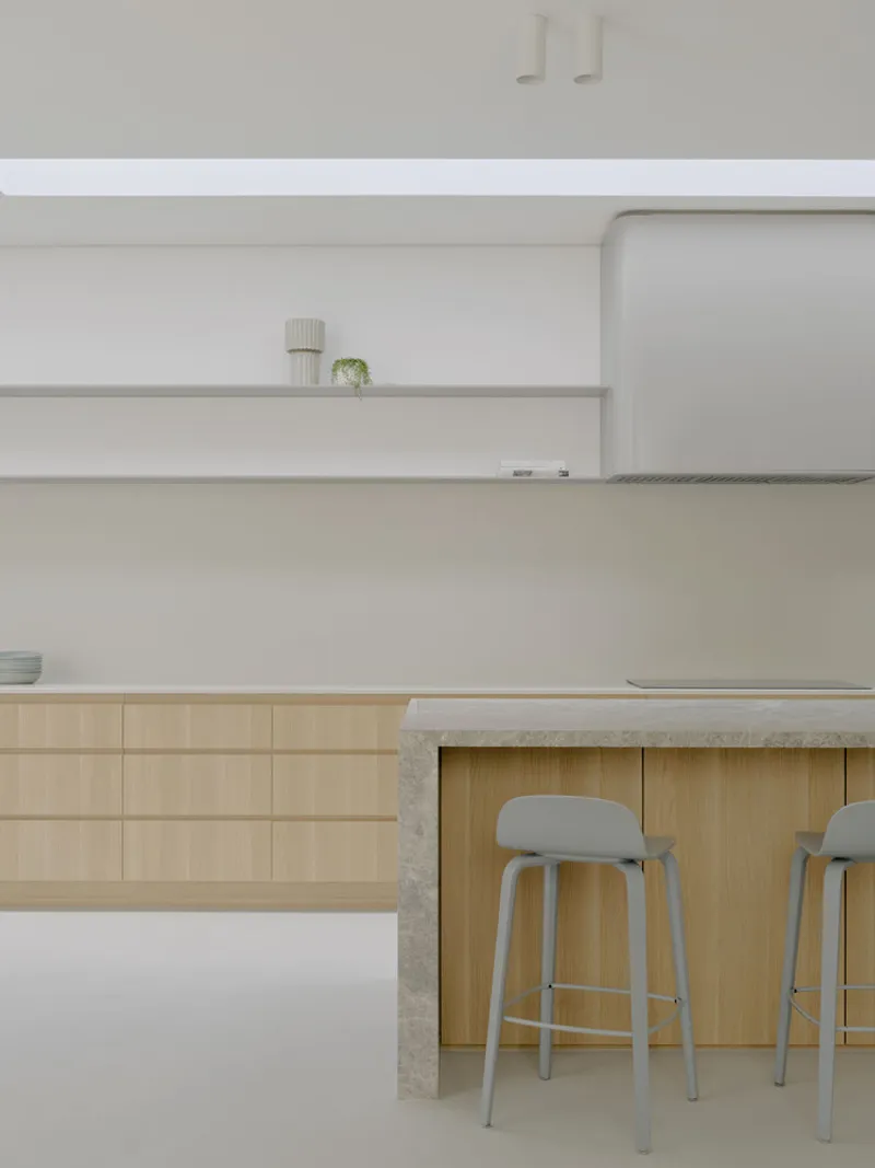 Kitchen island with timber base and concrete countertop under floating white shelves