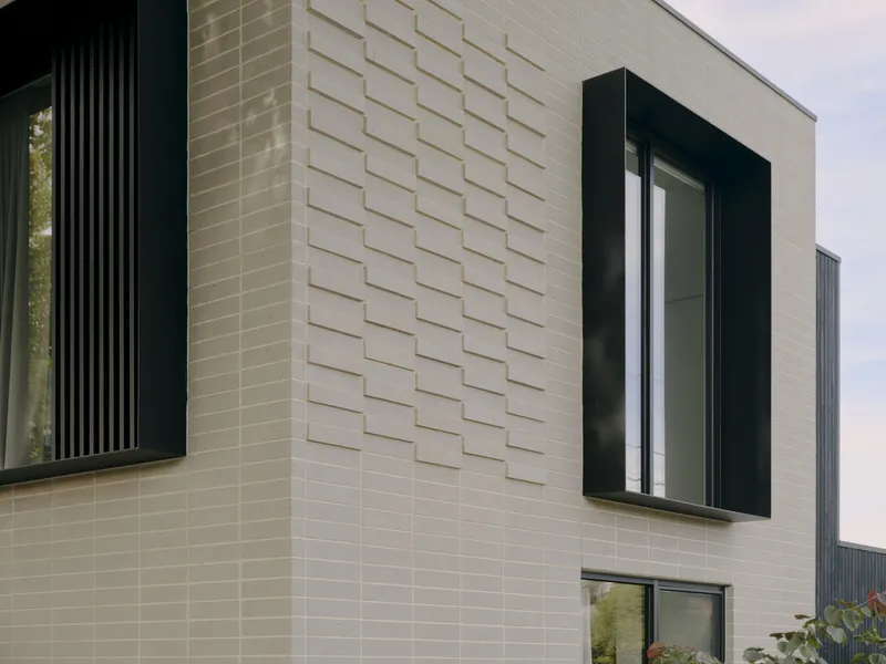 Facade detail showing cream and grey tile cladding with recessed black-framed windows