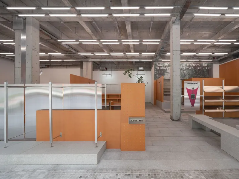 Retail checkout zone with translucent partitions and orange display units under exposed concrete structure and linear lighting