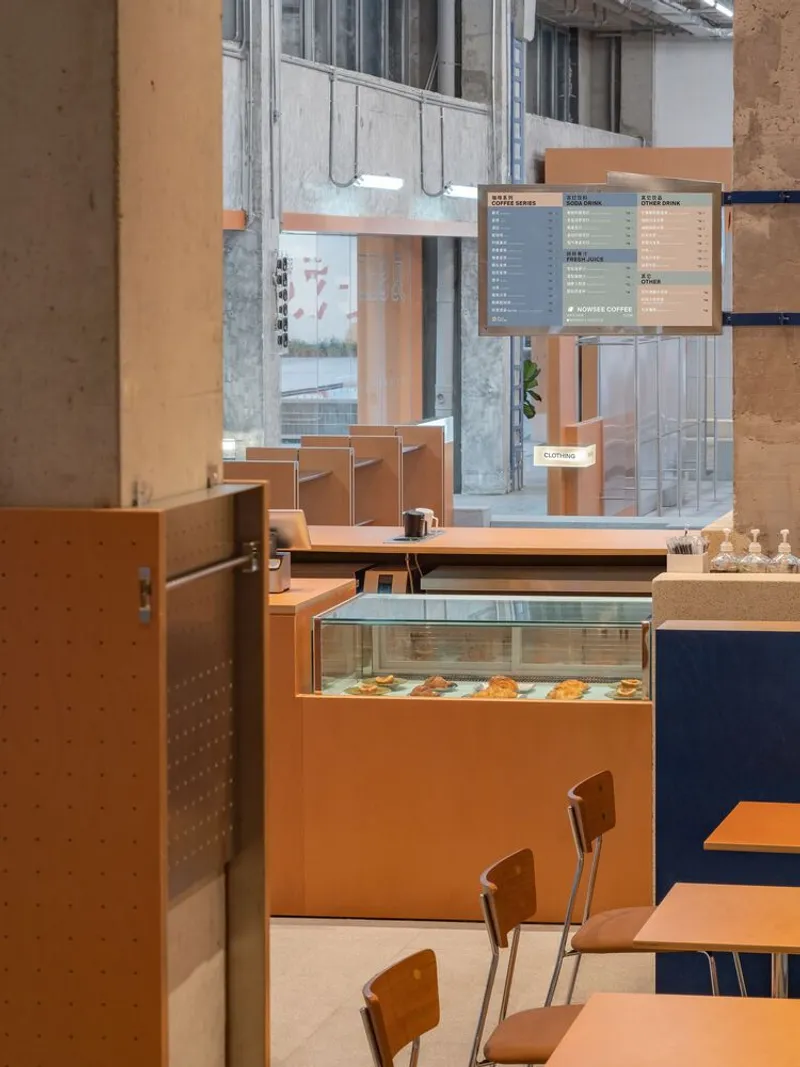 Cafe counter with glass pastry display case and hanging menu board beneath mezzanine level