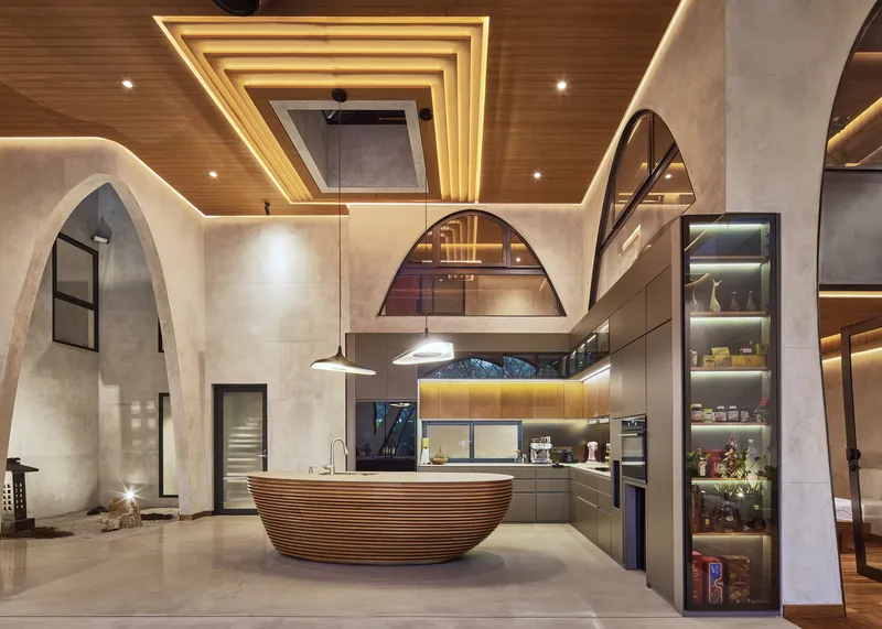 Kitchen with ribbed timber island beneath layered ceiling coffers and arched niches in concrete walls