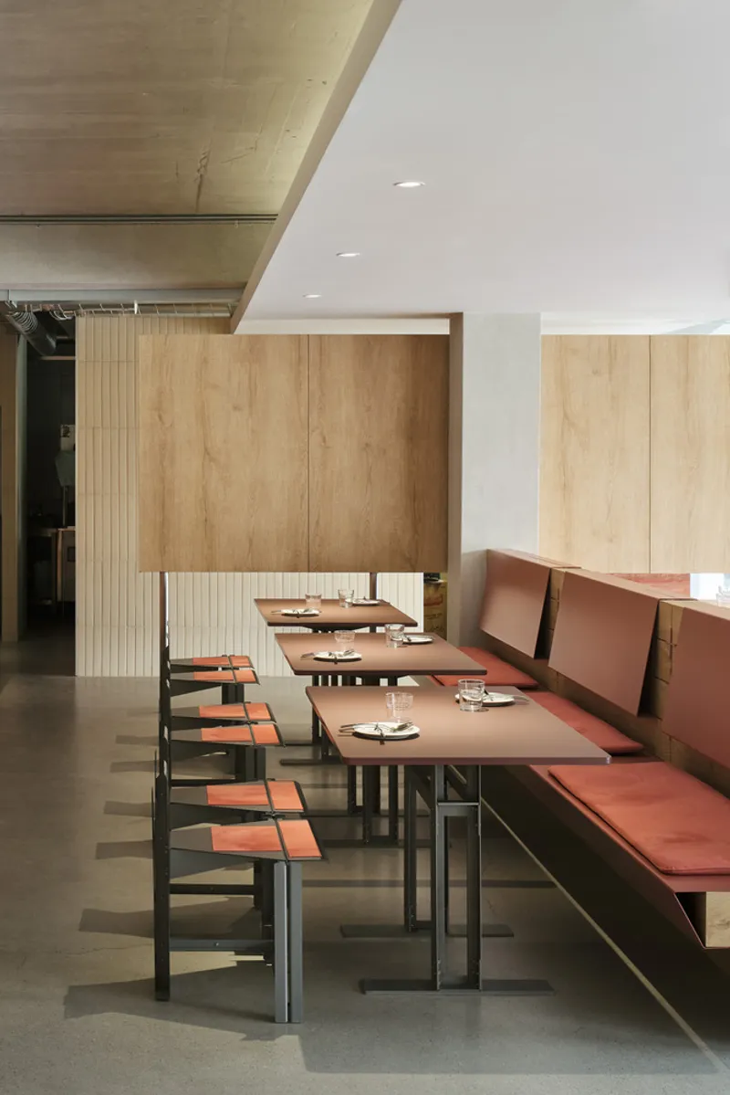 Close-up of banquette seating with timber partition, concrete ceiling and polished floor