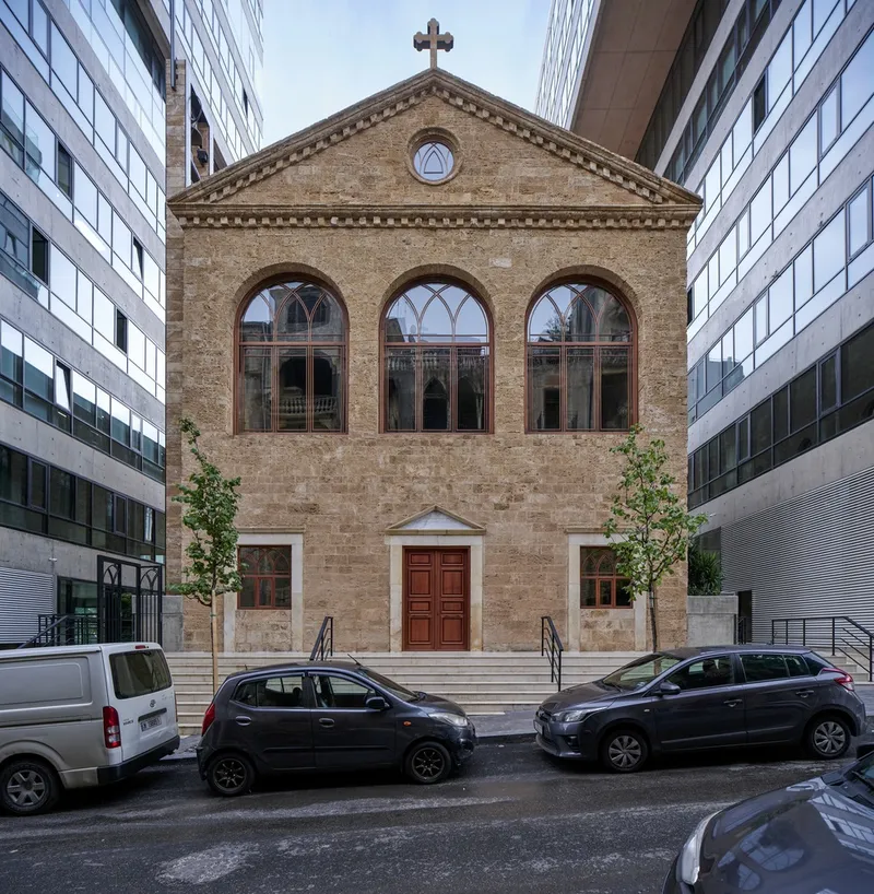 Street view of the chapel entrance with triple arched windows and timber door flanked by parked cars