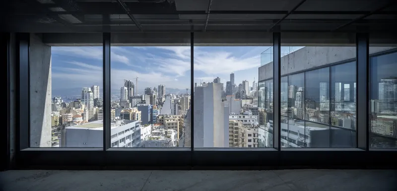 Floor-to-ceiling glazing framing a view of the dense urban skyline under a partly cloudy sky