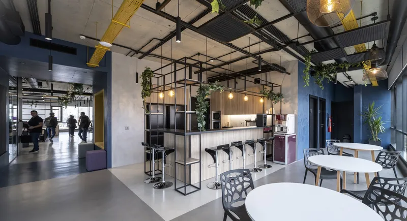 Freestanding steel-frame kitchenette with integrated bar seating, pendant lights, and trailing plants overhead