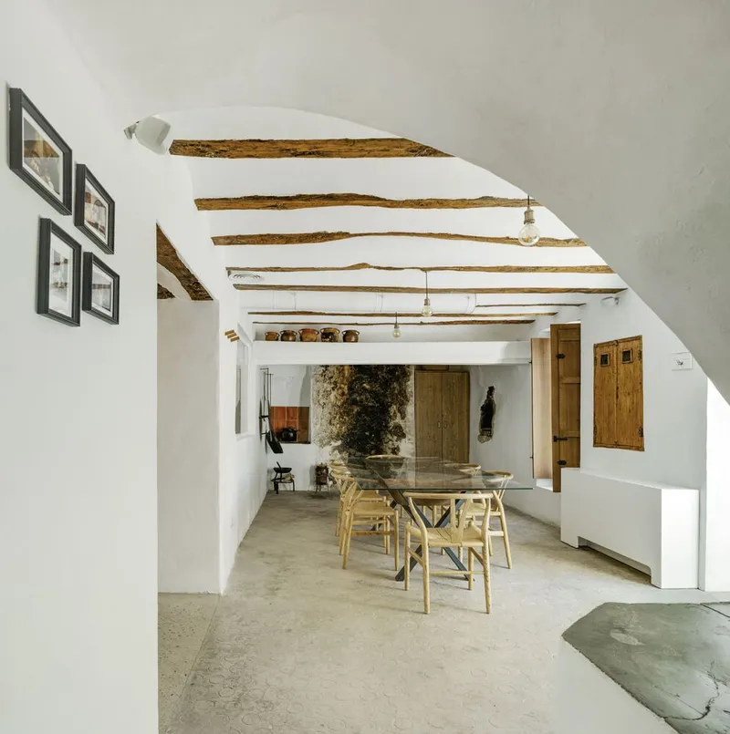 Dining area with exposed timber ceiling beams and a polished concrete floor in afternoon light