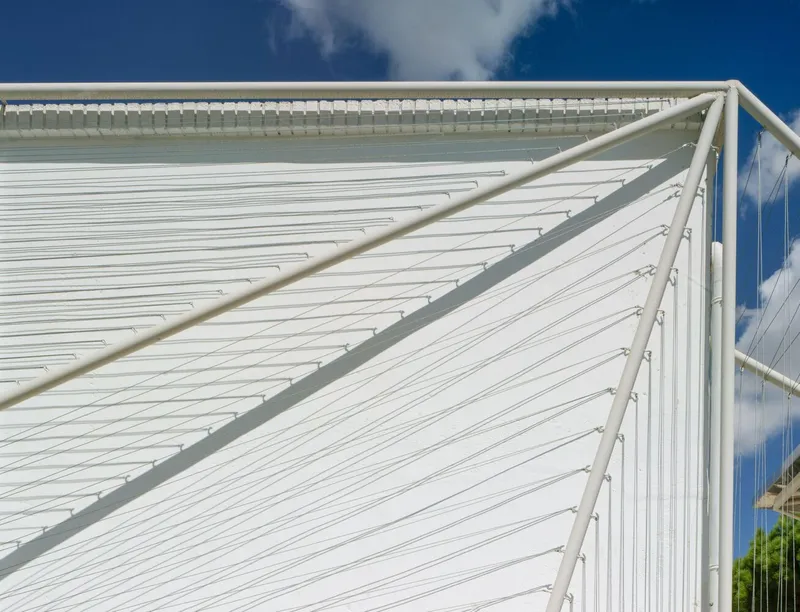 Close-up of the white ridged roof surface with tubular steel edge framing against blue sky