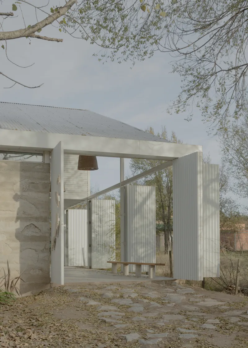 Open passageway framed by white painted timber columns and corrugated metal siding in afternoon light