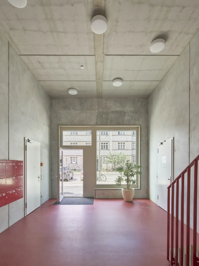 Concrete entrance hall with pink resin floor and circular ceiling lights facing the street glazing