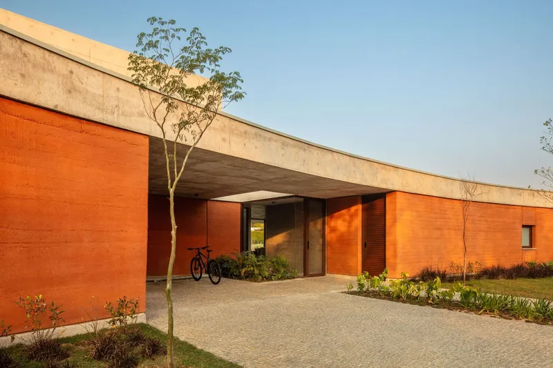 Covered entry portal with exposed concrete soffit framing the glazed door and terracotta walls