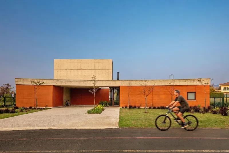 Street view of the terracotta panel facade with concrete volume above as a cyclist passes